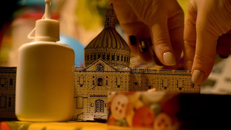 Female hands assembling Saint Pauls Cathedral building model at home. Hobby and leisure