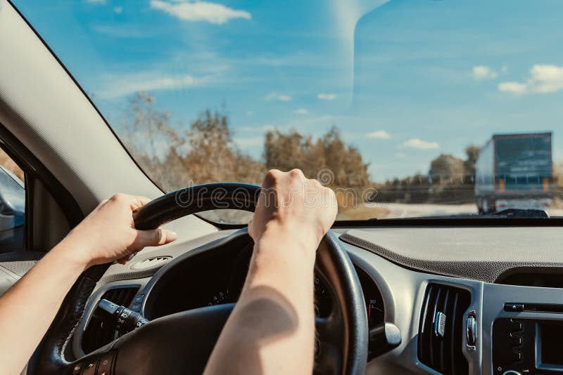 Female Hands Confidently Hold Steering Wheel of Car while Driving on Suburban Highway with