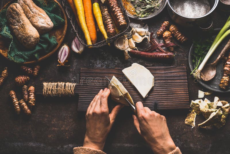 Female hands cutting celery on dark rustic kitchen table background with various vegetables and utensils. Root vegetables cooking stock photos
