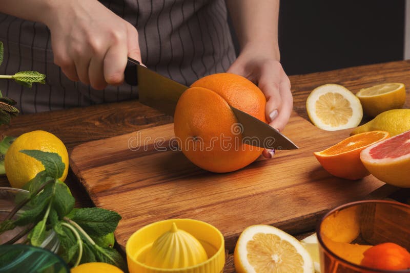 Female hands cutting citrus fruits on wooden board