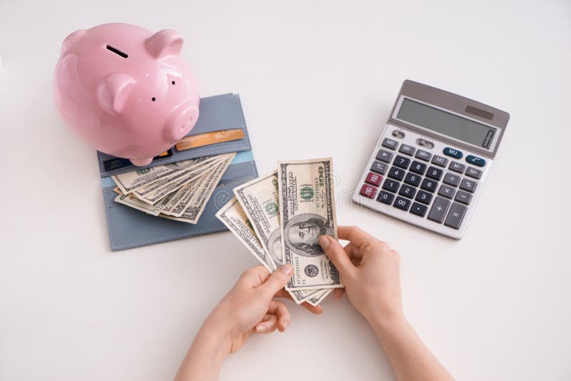 Female hands with dollars, piggy bank, wallet and calculator on white background, top view royalty free stock photos Female hands with dollars, piggy bank, wallet and calculator on white background, top view royalty free stock photos