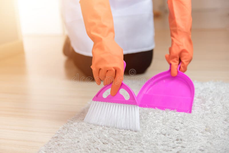 Female hands in orange gloves sweeping a carpet brush, Cleaning service concept, Close-up