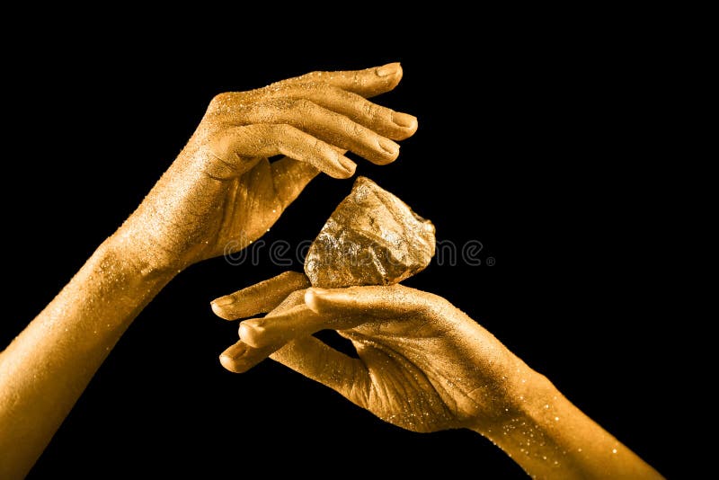 Female hands with gold nugget on black background stock images