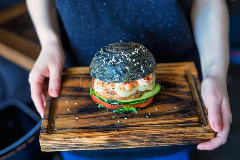 Female Hands Hold Black Burger With Prawns Stock Photo ...