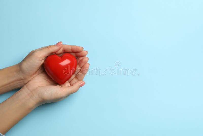 Female hands holding heart on blue background, space for text royalty free stock photography