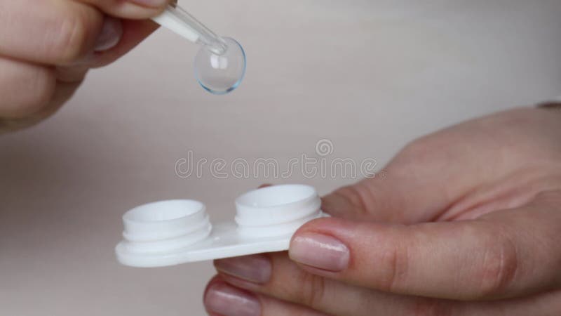 Female hands holding open contact lens case and gently picking up soft stock video