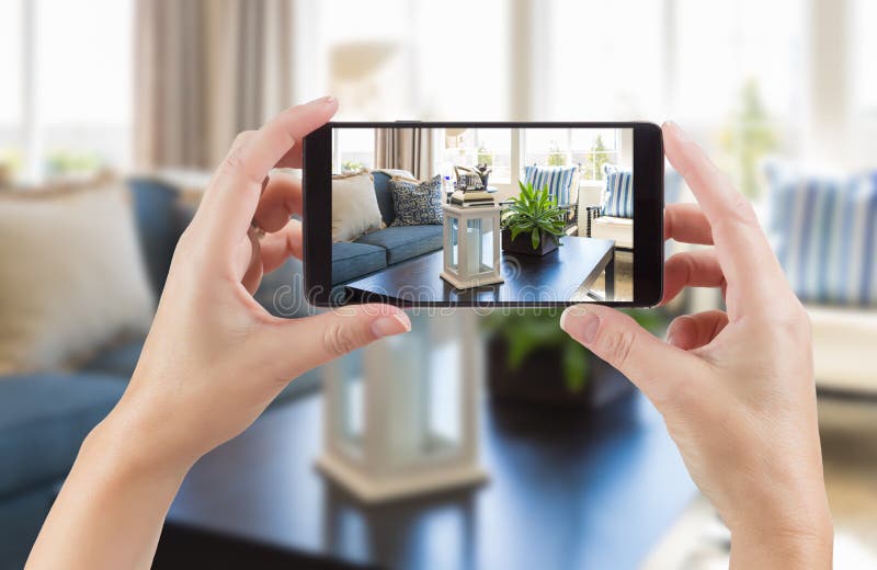 Female Hands Holding Smart Phone Displaying Photo of House Inter