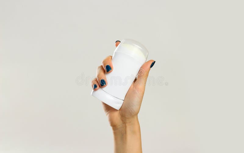 Female hands holding white deodorant. Isolated on gray background. Closeup.