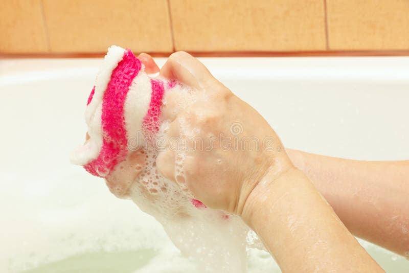 Female hands lathering striped sponge with soap stock photo Female hands lathering striped sponge with soap stock photo