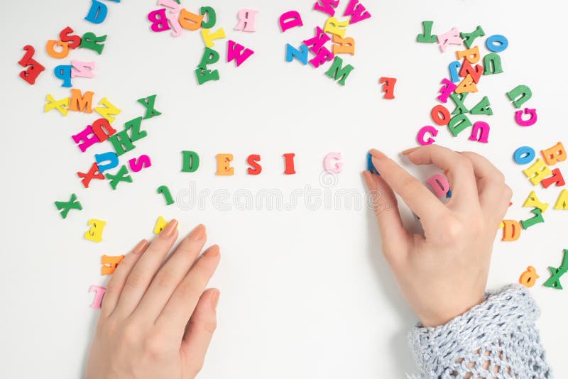 Female hands lay out of colorful letters the word design stock photography