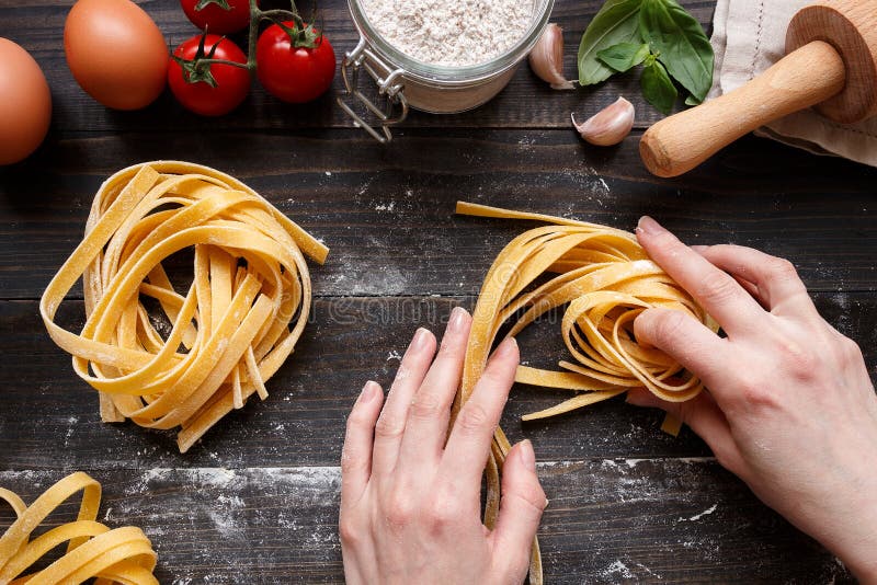 Female Hands Making Fresh Homemade Pasta. Pasta Ingredients On The Dark