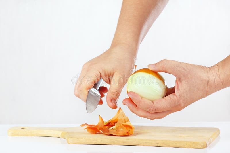 Female Hands Peeling Raw Onion with a Knife on a Cutting Board Stock