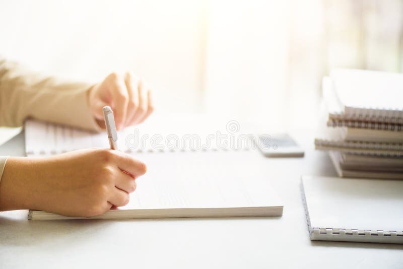 Female hands with pen writing on notebook. Back to school concept. Student from university learning languages.