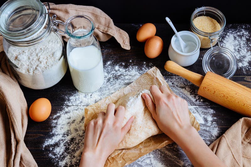 Female Hands Preparing Dough in the Kitchen. Baking Ingredients on the Wooden Table Stock Photo