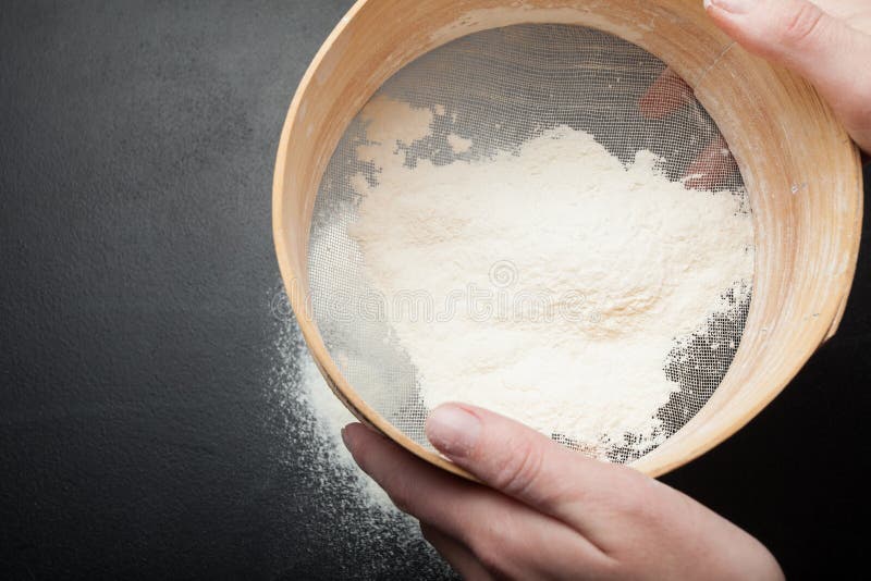Female hands sift flour on a black background, top view stock photography Female hands sift flour on a black background, top view stock photography