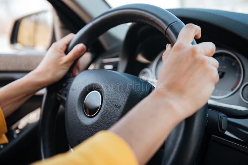 Female hands on steering wheel while driving a car stock images