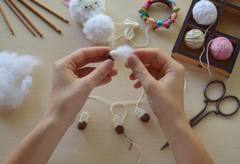 Female hands tying thread during amigurumi toy making process handmade crochet sheep toy step with wool and tools visible creative royalty free stock photography