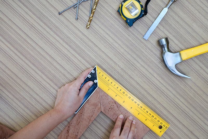 hands using a try square to check that the woodworking corners are square with a set collection of working hand tools