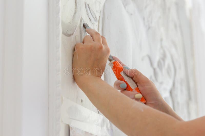 Female hands at work, a chisel carves a bas-relief pattern royalty free stock photography Female hands at work, a chisel carves a bas-relief pattern royalty free stock photography