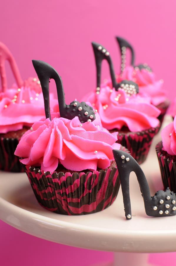 Female high heel stiletto shoes decorated pink and black red velvet cupcakes - close up on black cupcake.