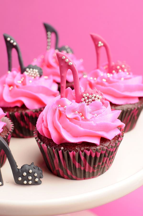 Female high heel stiletto shoes decorated pink and black red velvet cupcakes - close up on pink cupcake.