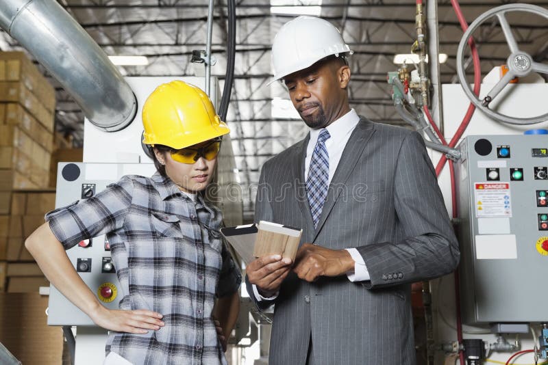 Female industrial worker and male engineer in discussion at timber factory stock photography Female industrial worker and male engineer in discussion at timber factory stock photography