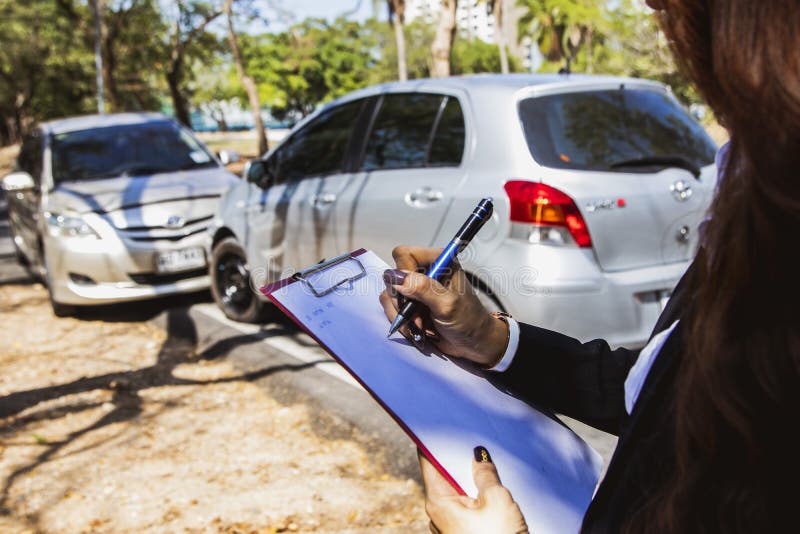Female insurer working at the scene responsible for helping get car insurance during car crash royalty free stock image