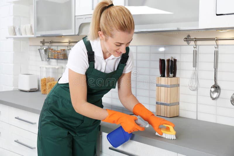 Female janitor cleaning kitchen counter with brush stock image Female janitor cleaning kitchen counter with brush stock image