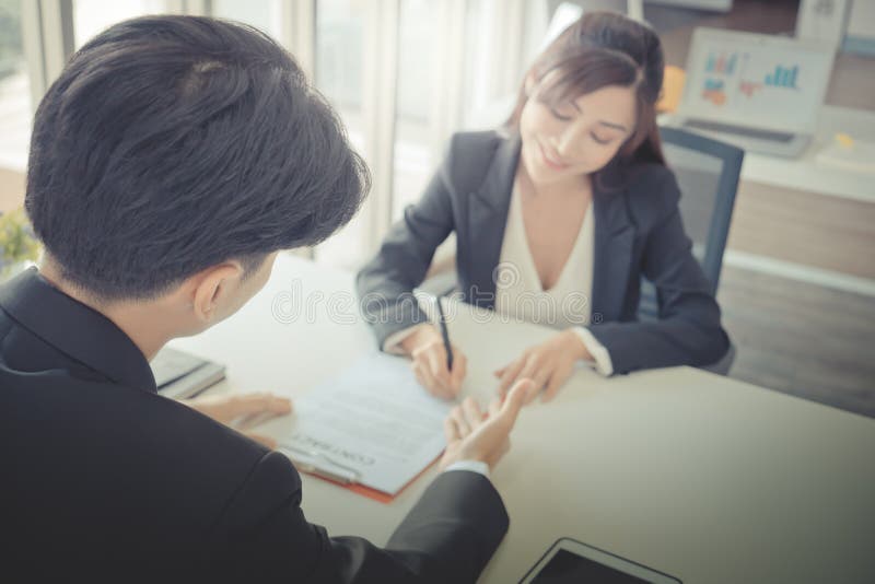 Female job candidate signing work contract with HR officer after a successful job interview stock images
