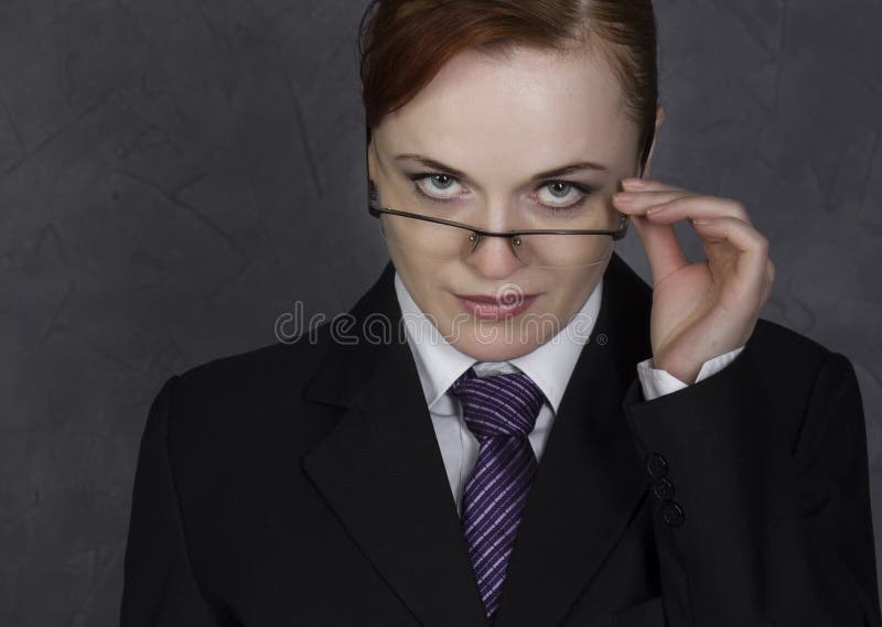 Female lawyer holding a big book with serious expression, woman in a man`s suit, tie and glasses