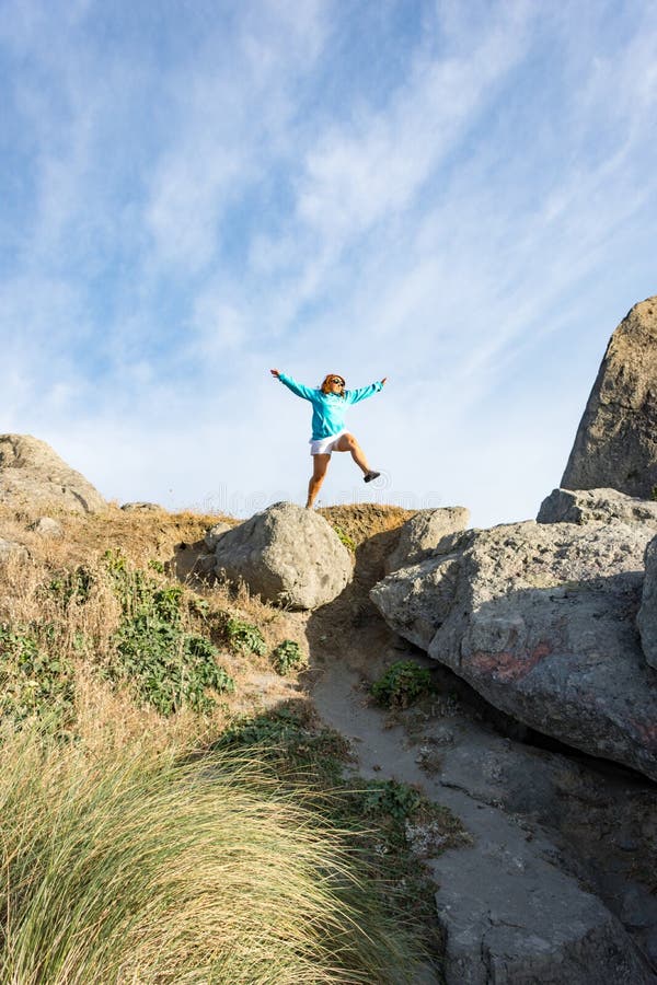 Female leaps off of a large rock along the Oregon Coast