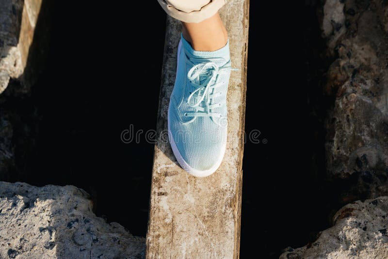 Female Legs In Beige Pants And Sneakers Are On The Board