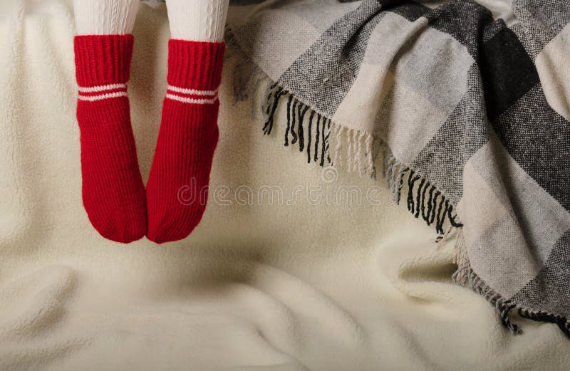 Female legs in warm white knitted tights and red socks on a whit