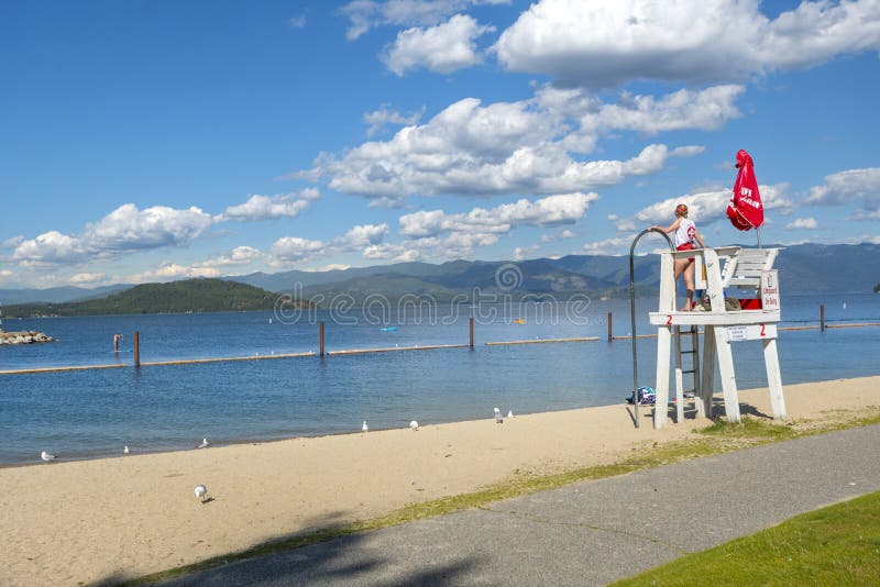 A female lifeguard stands on duty at her lifeguard station along the sandy city beach at Sandpoint, Idaho stock photos A female lifeguard stands on duty at her lifeguard station along the sandy city beach at Sandpoint, Idaho stock photos