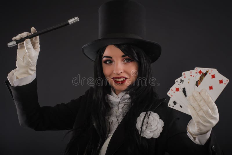 Female magician in performer suit with magic wand and playing ca royalty fr...