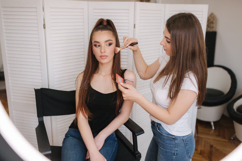 Female makeup master use a powder brush. Beautiful model in beauty studio. Professional make up artist finish fashion stock photos Female makeup master use a powder brush. Beautiful model in beauty studio. Professional make up artist finish fashion stock photos