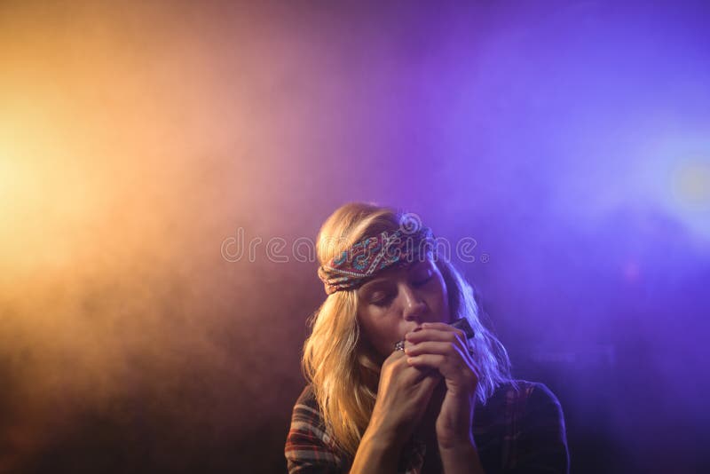 Beautiful female musician playing harmonica in nightclub