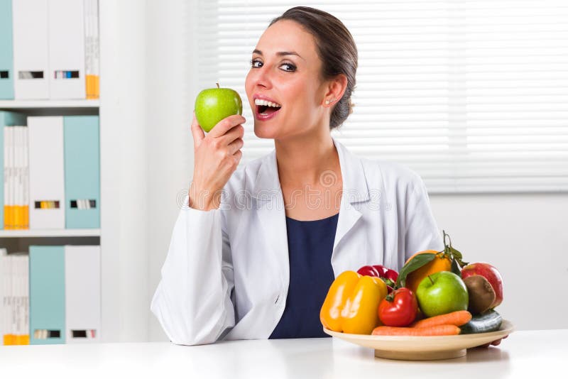 Female nutritionist eating a Green Apple in her office royalty free stock photo Female nutritionist eating a Green Apple in her office royalty free stock photo