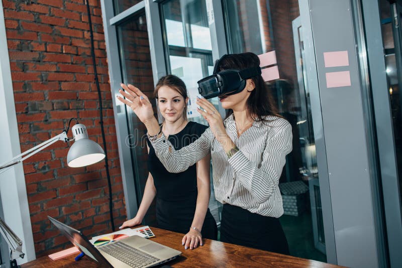 Female office workers having fun at work watching 3d video in VR goggles, woman touching something experiencing virtual stock photography