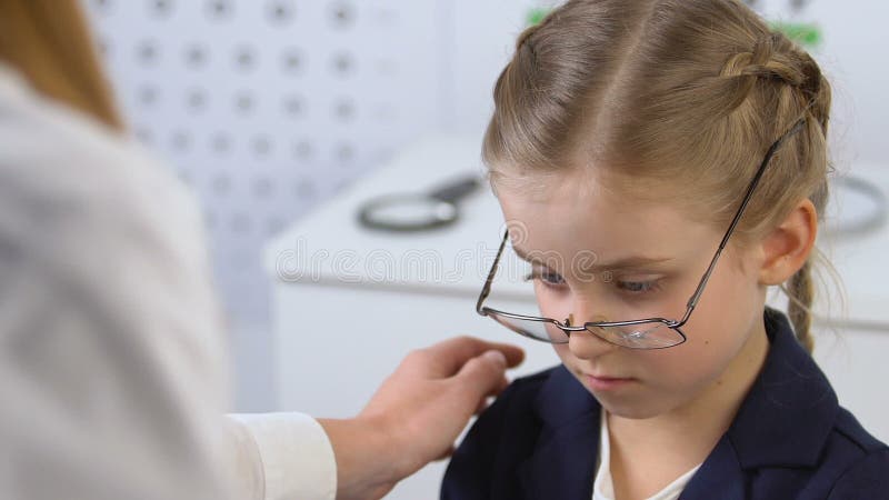 Female ophthalmologist comforting schoolgirl in broken eyeglasses, prescription