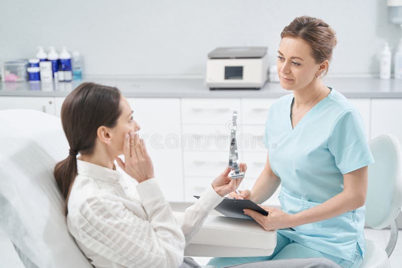 Woman Having Consultation With Doctor In Cosmetology Clinic Stock Photo