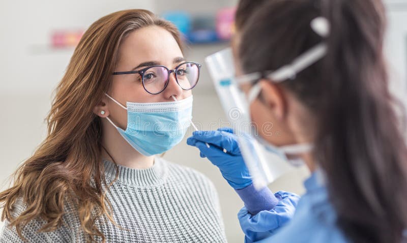 Female patient wearing mask over mouth is having sample taken from nose for a pcr test for Covid 19