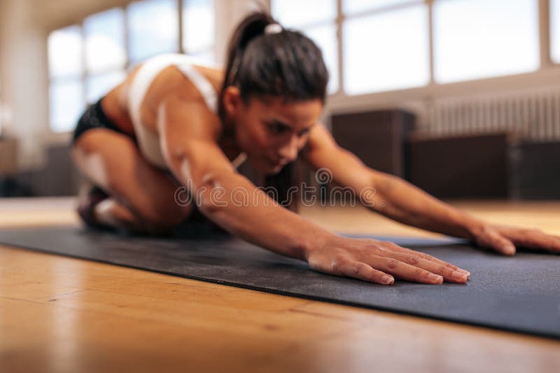 Female performing yoga on exercise mat at gym stock photo Female performing yoga on exercise mat at gym stock photo
