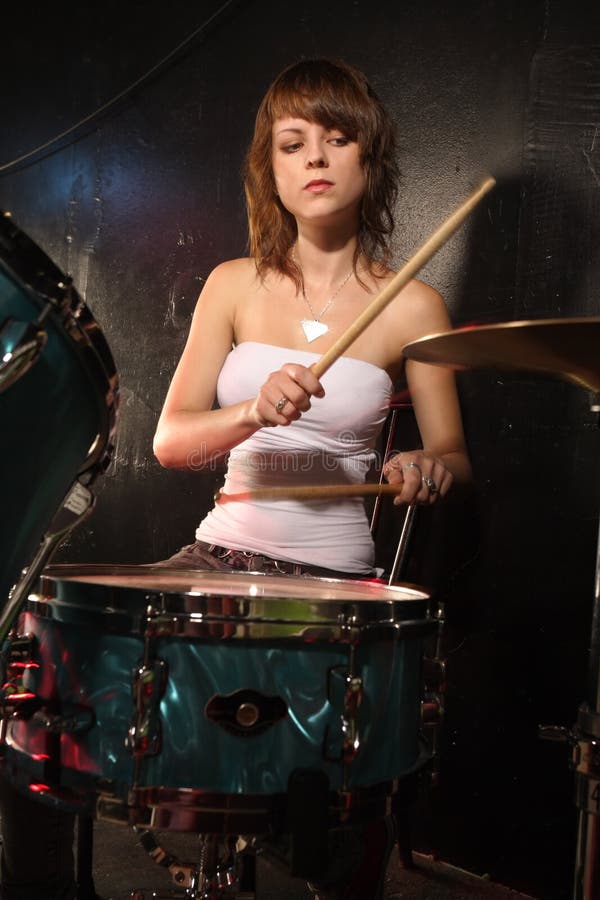 Photograph of a female drummer playing a drum set on stage. Photograph of a female drummer playing a drum set on stage.