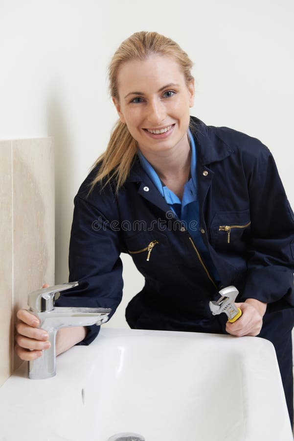 Female Plumber Working On Sink Using Wrench