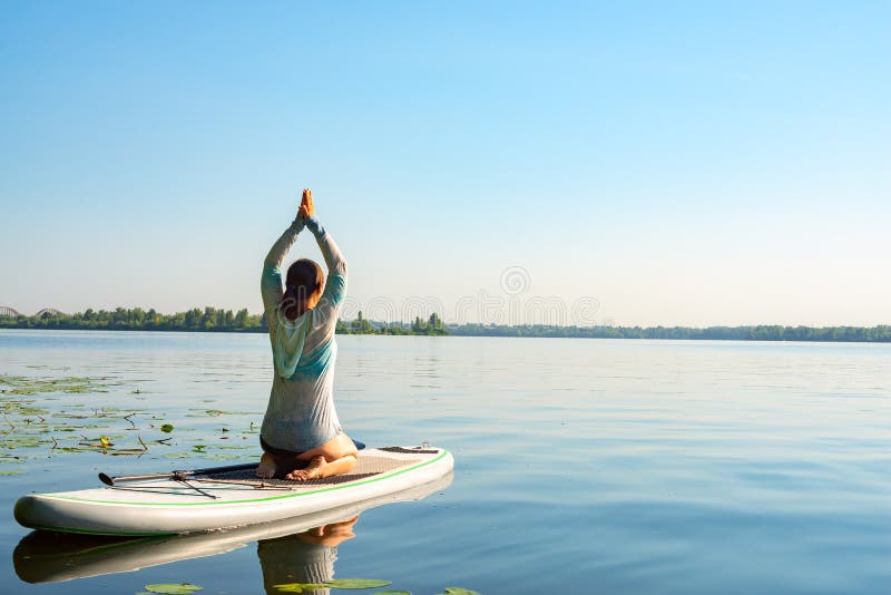 Female practicing yoga on a SUP board