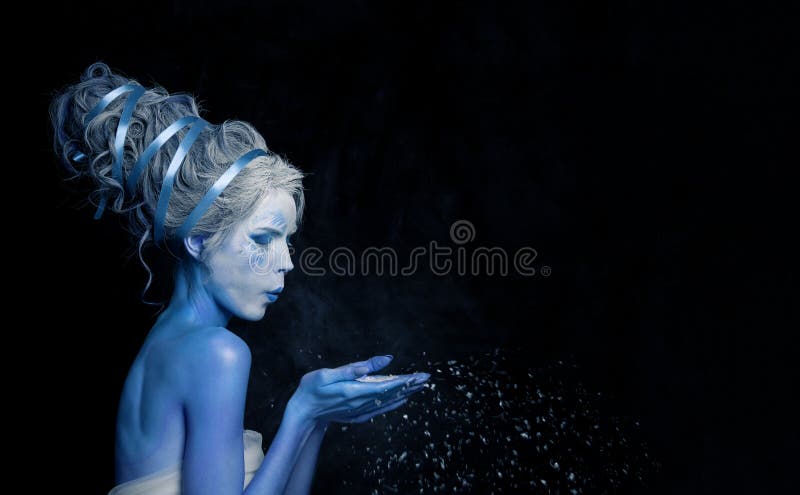 Female profile portrait. Young woman fairy actress with stage makeup and hairstyle blowing white snow on black banner background.