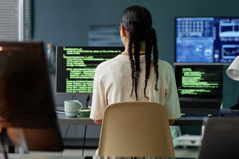 Female Programmer Coding on Multiple Computers at Professional Workstation in Office stock image