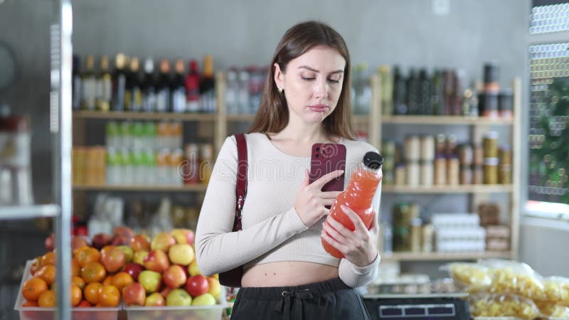 Female purchaser scanning QR code or barcode of grapefruit juice in supermarket stock video