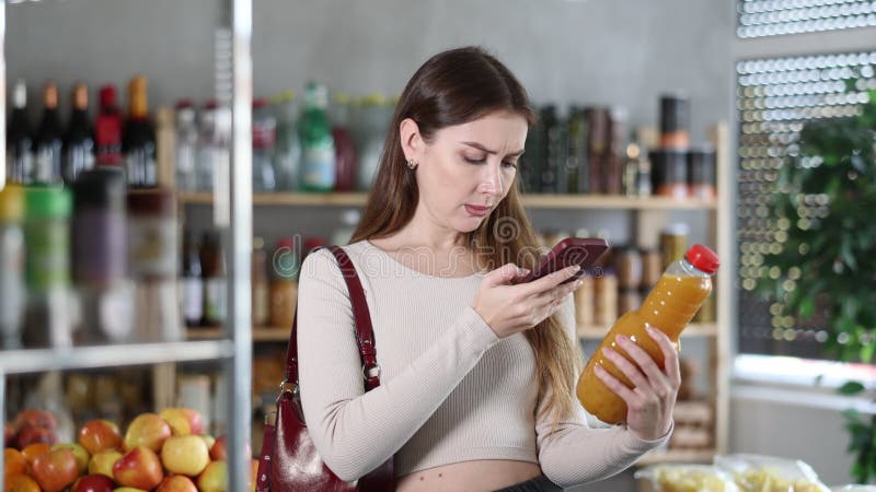 Female purchaser scanning QR code or barcode of peach juice in supermarket stock video